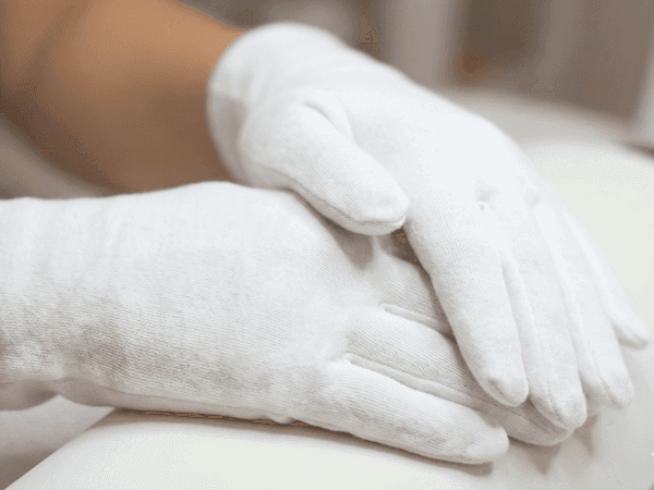 Mani con guanti di cotone per unghie forti e resistenti
