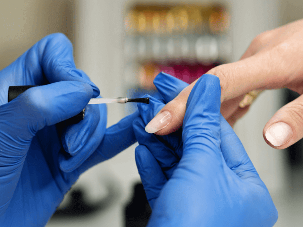 Applicazione di smalto semipermanente professionale su unghie naturali durante un trattamento in salone.